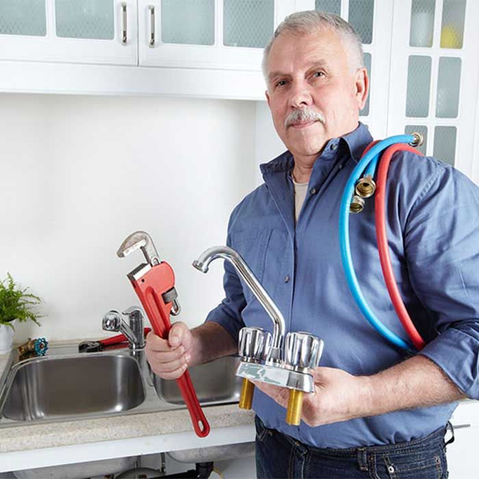 Technician holding plumbing parts in a kitchen